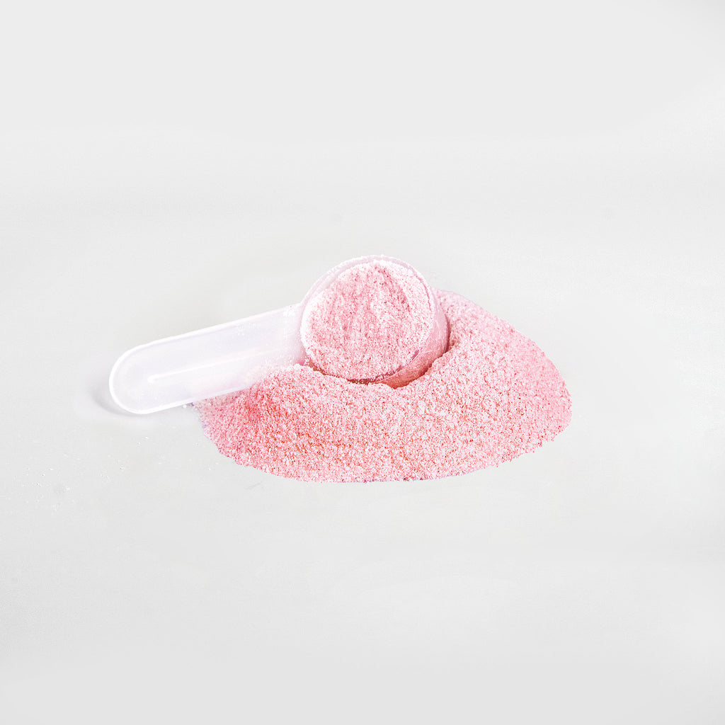 Pink bath bomb with a white scoop on a light gray background