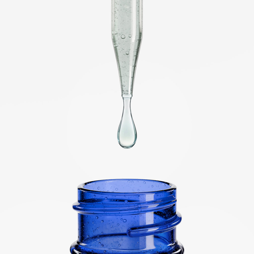 Glass dropper with clear liquid above a blue container on a white background