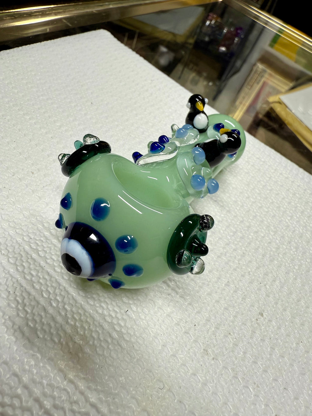 Ripkitty penguin art spoon pipe in mint green — sculpted penguin figures on top, blue dot pattern, dark green flipper accents, white background