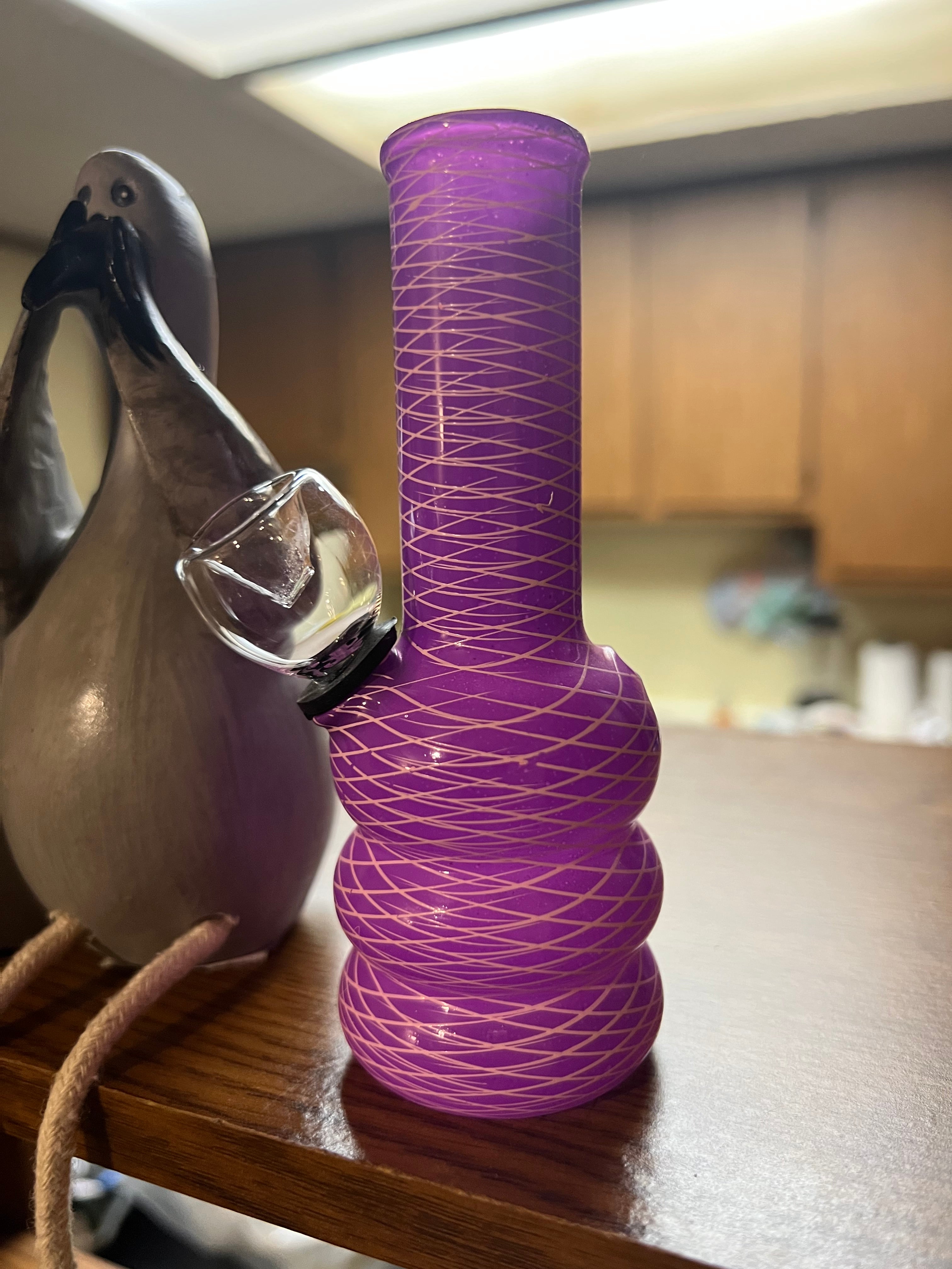 Ripkitty 5-inch soft glass water pipe, purple with gold net texture pattern, full side profile, bubble base, clear bowl piece, decorative bird figurine beside it.