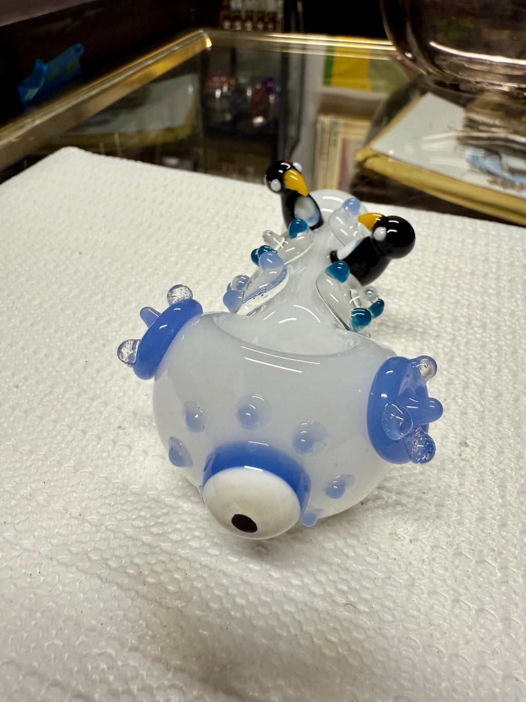 Close-up of Ripkitty penguin art pipe bowl — evil eye glass accent with blue ring on periwinkle body, penguin sculpts in background