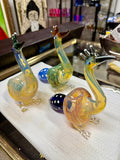 Ripkitty 5" peacock art borosilicate glass hand pipe — yellow-amber body with teal stripe detailing, sculpted peacock neck and beak mouthpiece, blue polka-dot bowl, white background
