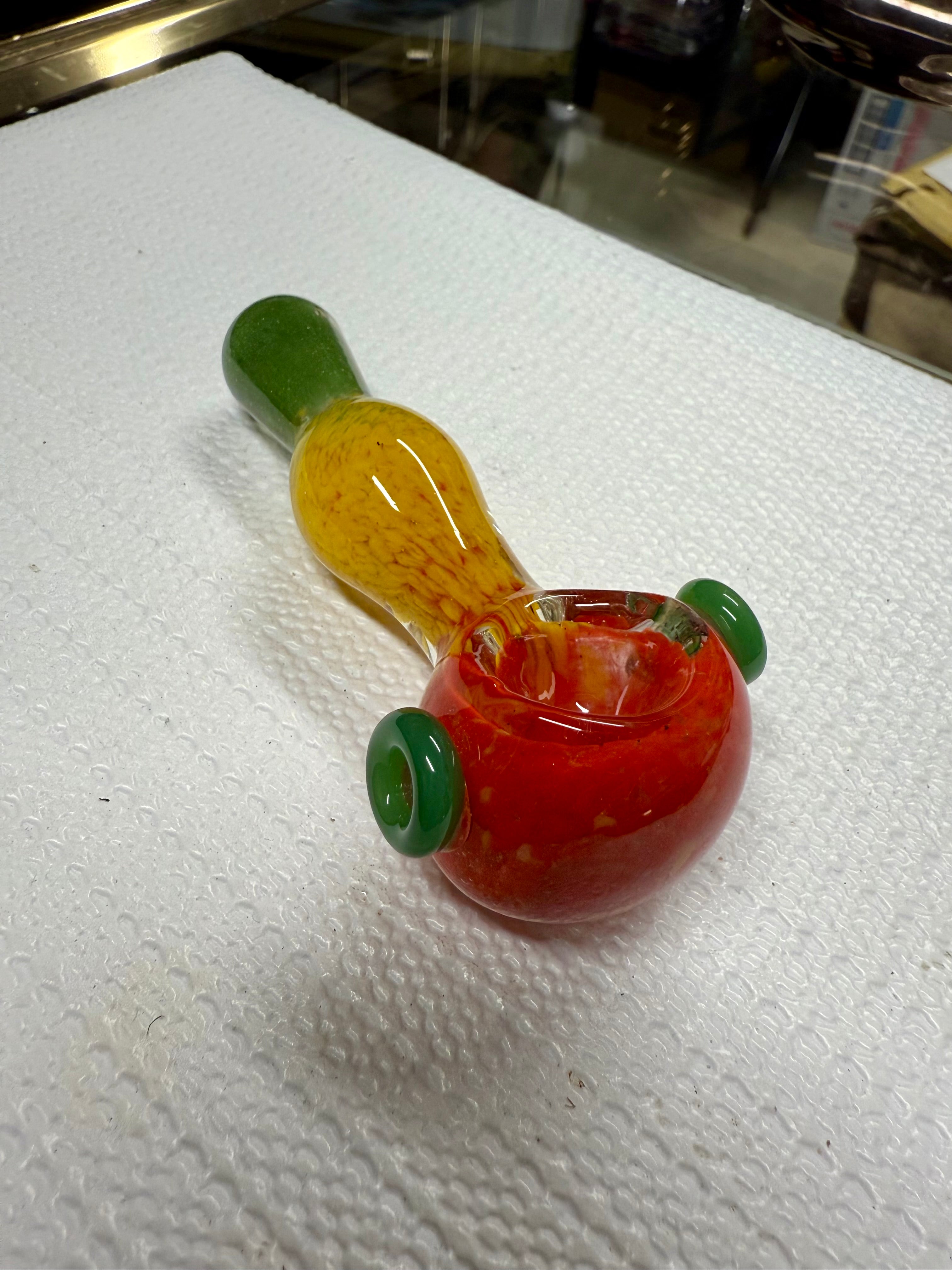 Ripkitty 3.5" Rasta art spoon pipe — handblown glass in red, yellow, and green rasta colorway with green marble accents, displayed on white surface