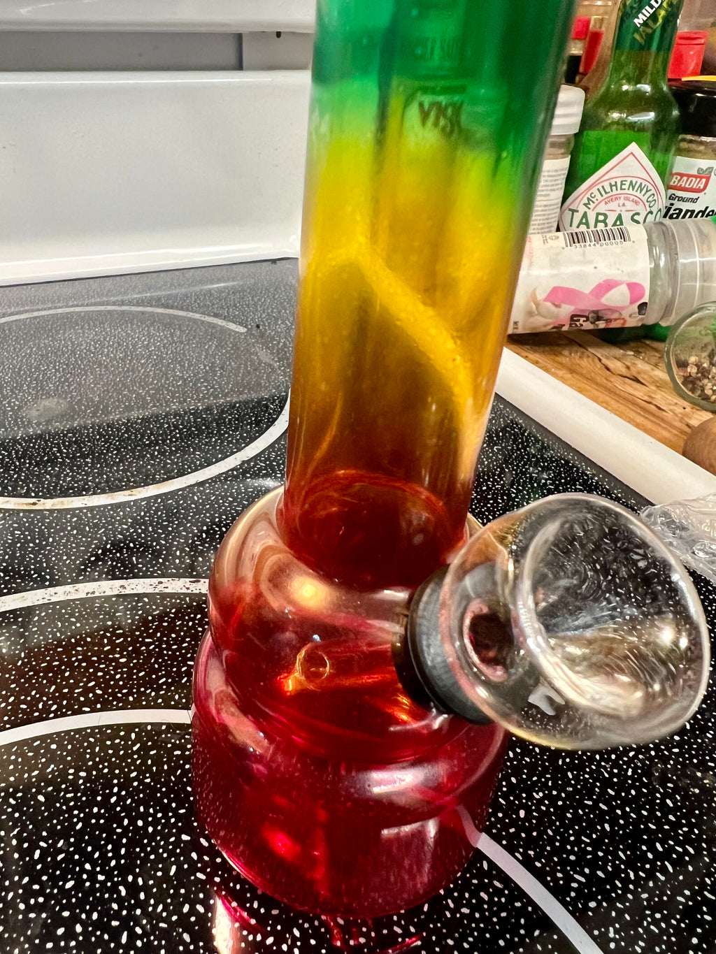 Ripkitty 5-inch soft glass water pipe, rasta red-yellow-green gradient colorway, full side profile with bowl piece, black stovetop background