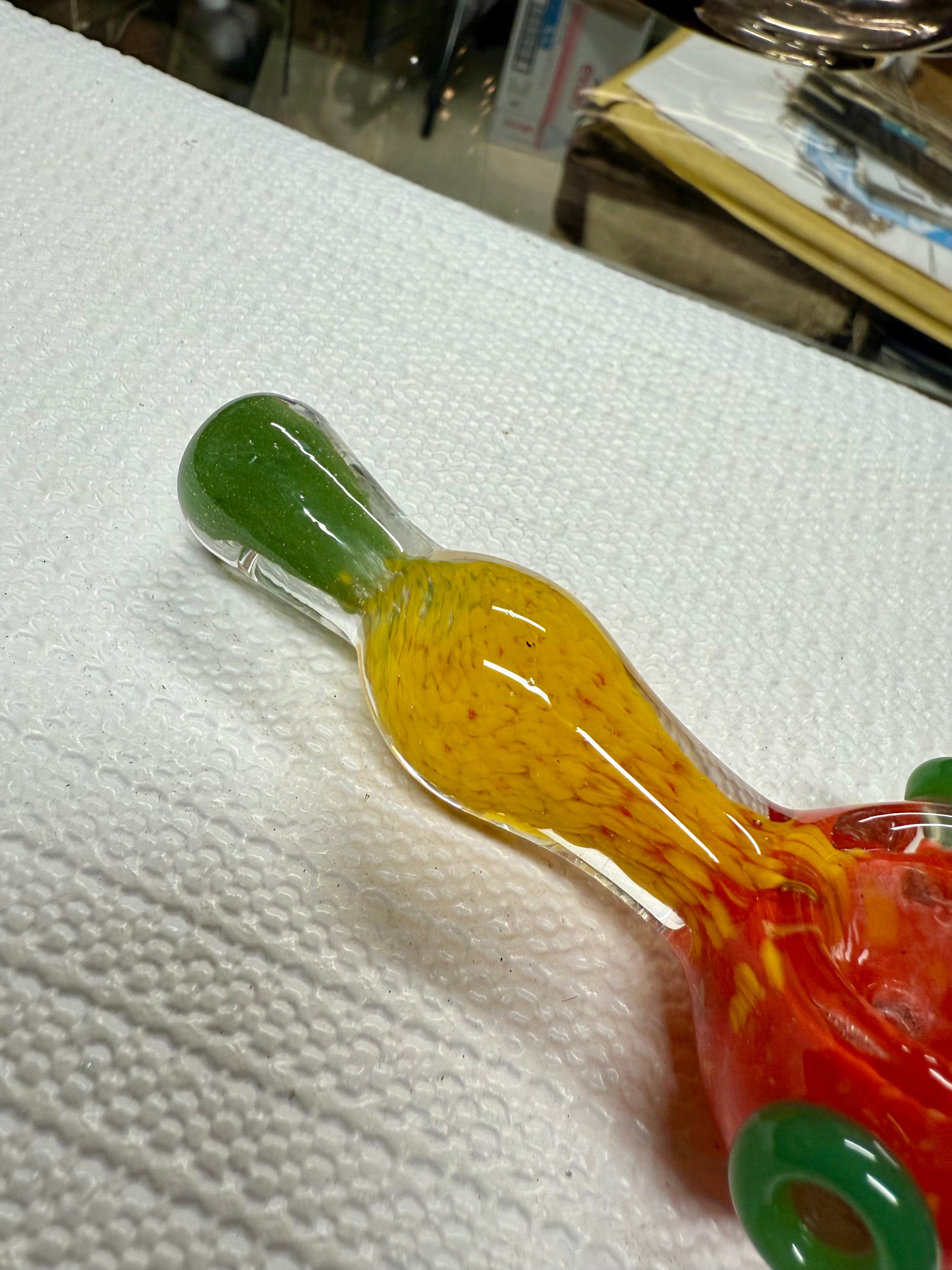  Close-up of Ripkitty rasta spoon pipe mouthpiece — green glass tip with yellow frit body and red bowl visible in background