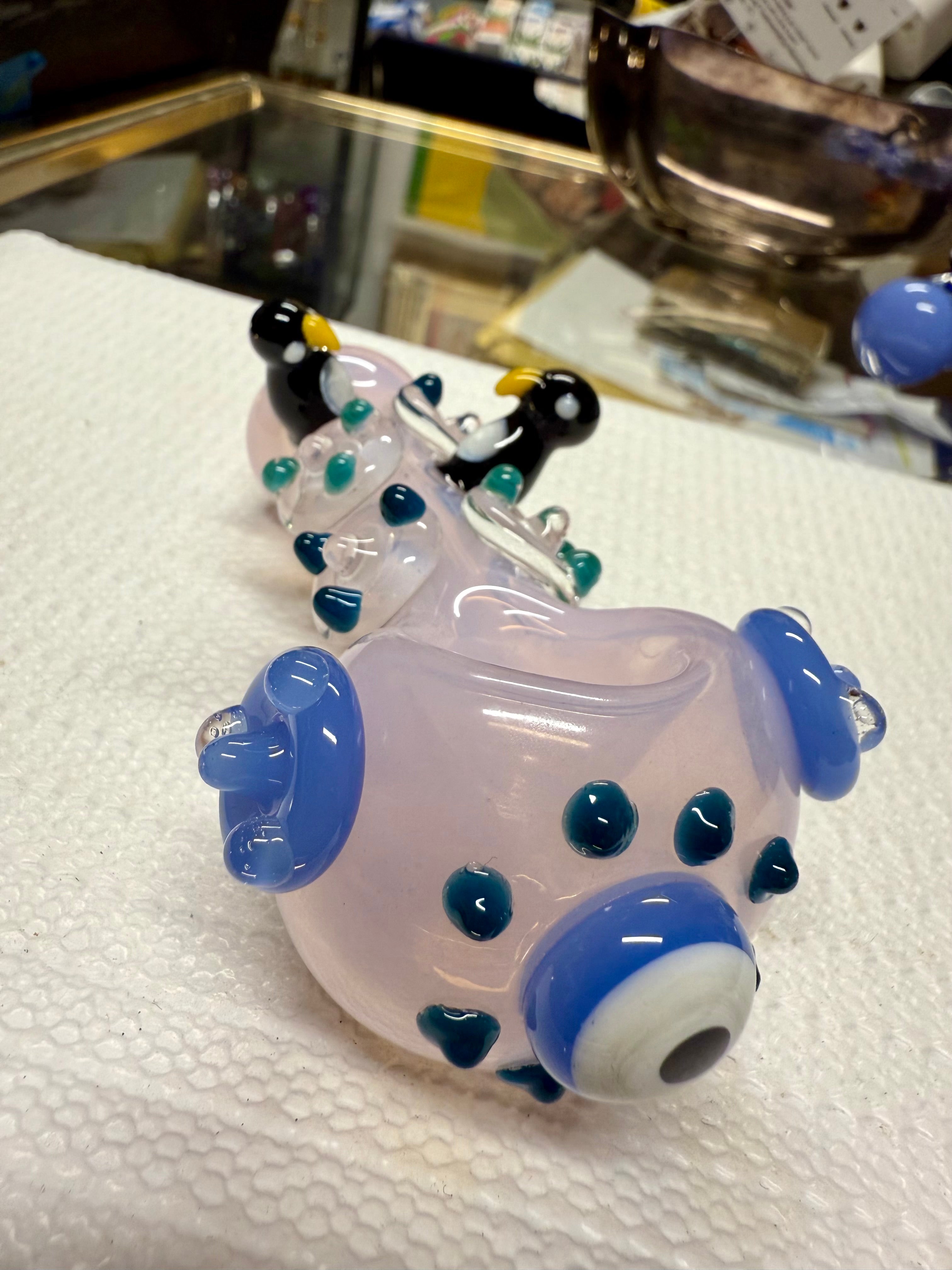 Top-down view of Ripkitty penguin art spoon pipe — pink with penguin figures and blue dot pattern visible from above